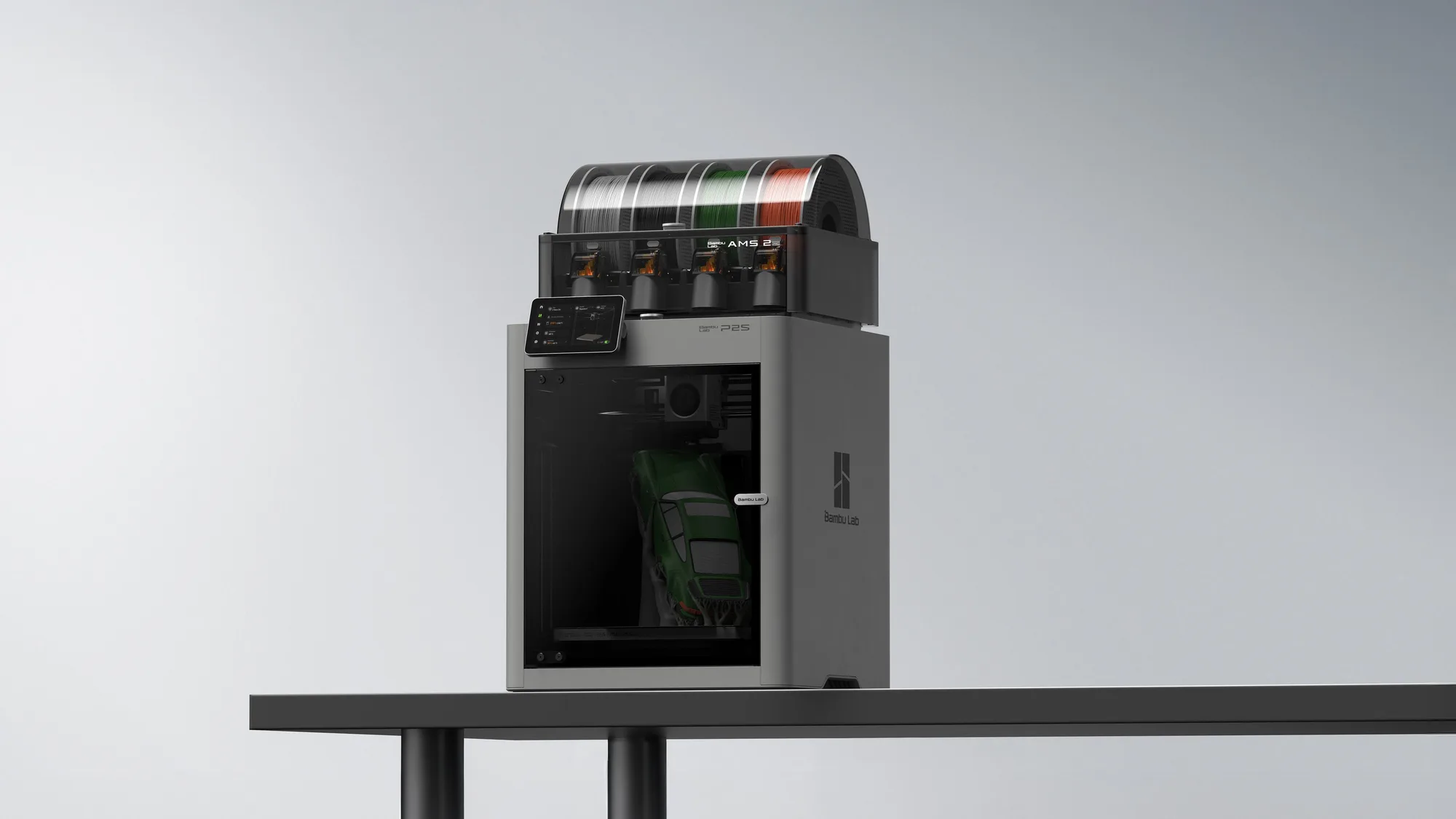 Bambu Lab P2S enclosed 3D printer with an AMS 2 filament unit on top standing on a dark table against a pale grey gradient backdrop