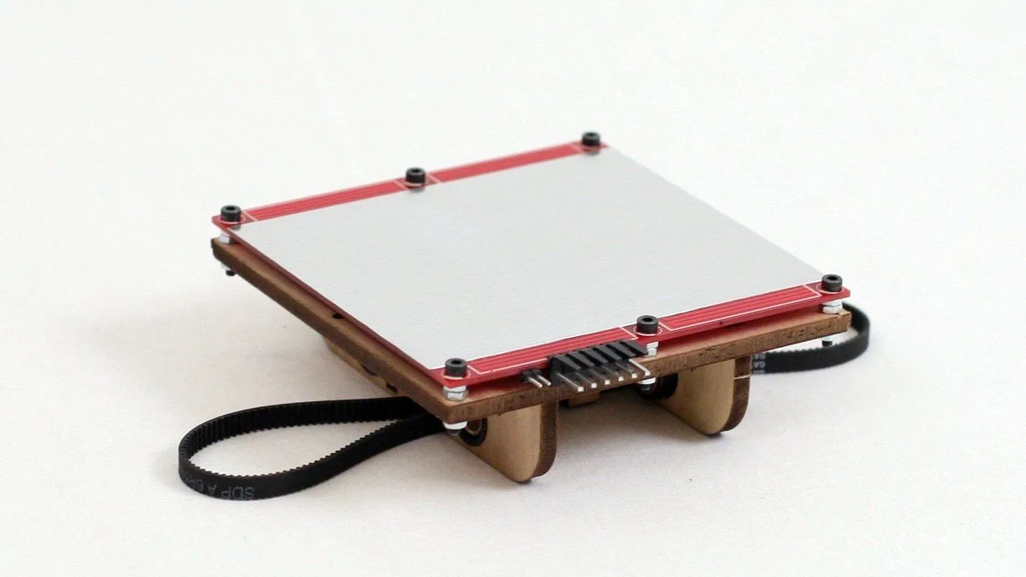 A bare heated build platform with a flat silver print surface, red edges and screw corners on a white background