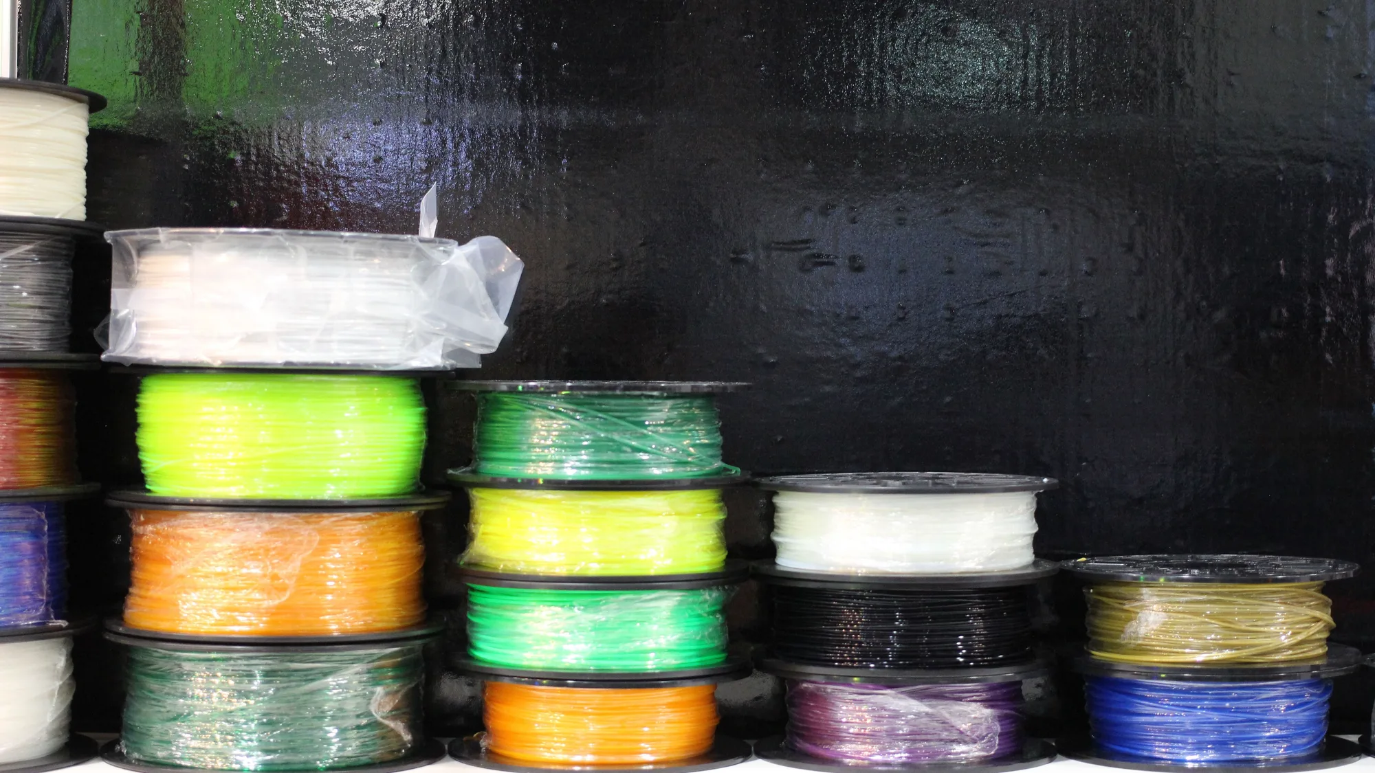 Stacks of 3D printer filament spools in many colours on a shelf